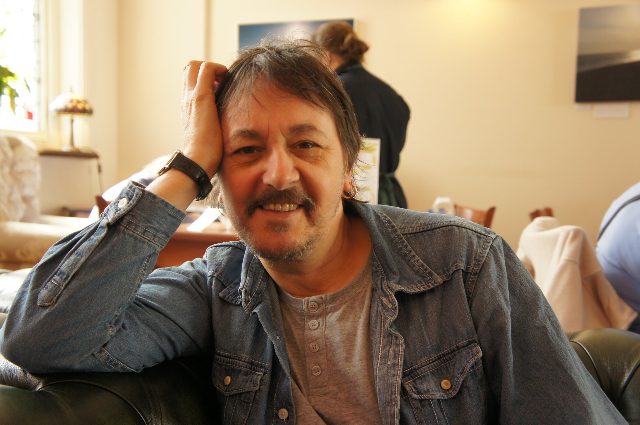 Patrick Jasper Lee seated in a living room, smiling towards the camera.